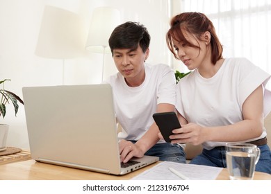 Smiling Young Husband And Wife Filling Insurance Claim Form Online On Laptop And Entering Personal Information