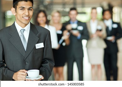 Smiling Young Indian Businessman Having Coffee Break During Seminar