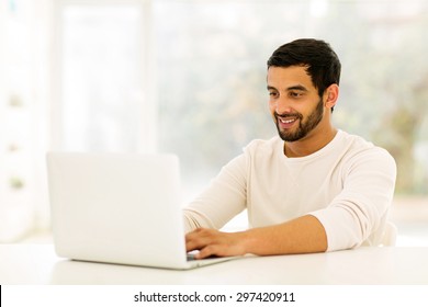 Smiling Young Indian Man Using Laptop At Home