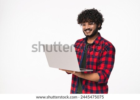 Smiling young Indian man using laptop for remote job isolated over white background. Happy Hindi freelancer student typing, doing online projects, e-commerce