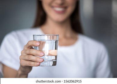 Smiling young lady holding fresh transparent pure filtered mineral water, happy healthy adult woman offering glass to camera as health care thirst hydration natural nutrition concept, close up view - Shutterstock ID 1562062915