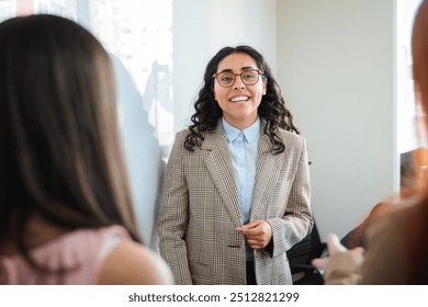 Smiling young latin businesswoman sharing business ideas with colleagues during a meeting on the whiteboard at office - Powered by Shutterstock