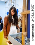 Smiling young Latin woman tourist wearing casual warm jacket and eyeglasses standing in Blue House of Frida Kahlo Museum in Mexico City and looking at exhibition