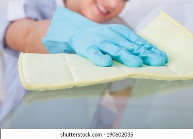 Smiling Young Maid Cleaning Glass Table At Home