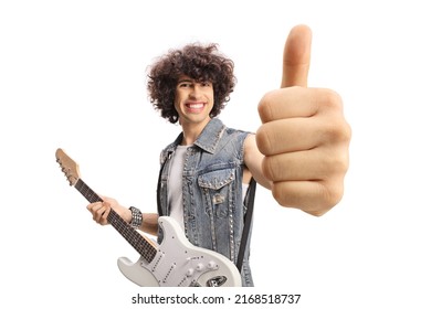 Smiling young male in a denim vest with an electric guitar showing thumbs up isolated on white background