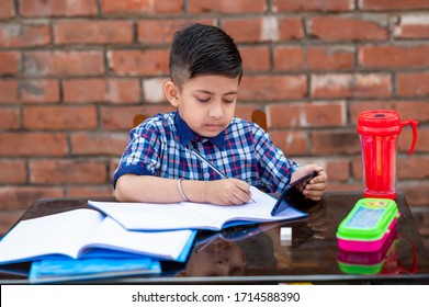Smiling young male kid using digital smartphone watching online e-learning video to studying in classroom , Asian Indian schoolboy study with Mobile phone. 
