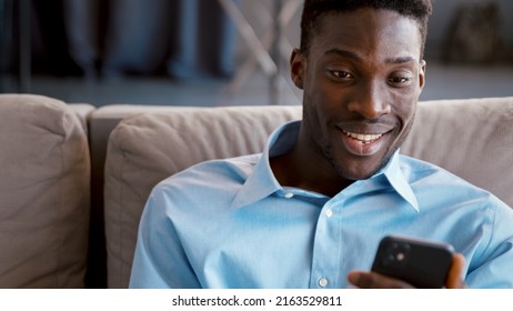 Lächeln junge Männer, die Nachrichten mit Smartphone auf dem Sofa zu Hause senden