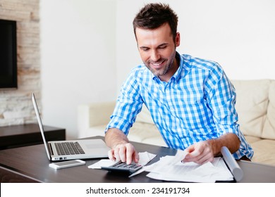 Smiling young man analyzing his expenses and paying online