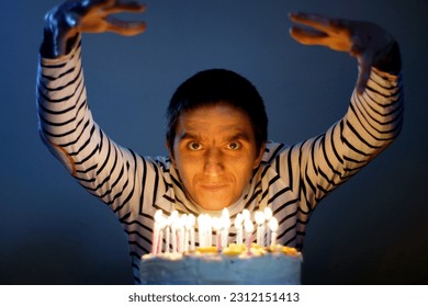 Smiling young man around while sitting in front of a cake with lit candles for his birthday - Powered by Shutterstock