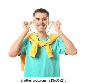 Smiling Young Man In Blue T-shirt Putting Earplugs On White Background