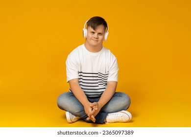 A smiling young man with cerebral palsy in glasses listens to music in headphones. World Genetic Diseases Day concept - Shutterstock ID 2365097389
