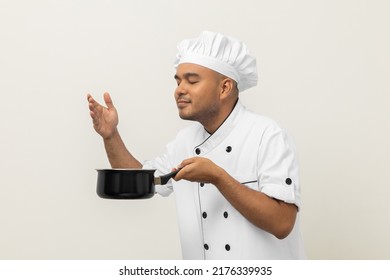 Smiling Young Man Chef In Uniform Gesture Smelling Empty Hot Pot Stew Soup Delicious Dish Menu Good Taste On Isolated. Cooking Man Occupation Chef People In Kitchen Restaurant And Hotel.