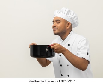 Smiling Young Man Chef In Uniform Gesture Smelling Empty Hot Pot Stew Soup Delicious Dish Menu Good Taste On Isolated. Cooking Man Occupation Chef People In Kitchen Restaurant And Hotel.