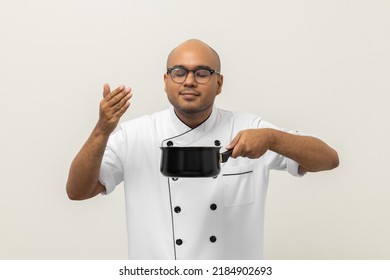 Smiling Young Man Chef In Uniform Gesture Smelling Empty Hot Pot Delicious Dish Menu Good Taste On Isolated. Cooking  Man Occupation Chef People In Kitchen Restaurant And Hotel.