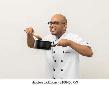 Smiling Young Man Chef In Uniform Gesture Smelling Empty Hot Pot Delicious Dish Menu Good Taste On Isolated. Cooking  Man Occupation Chef People In Kitchen Restaurant And Hotel.