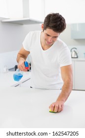 Smiling Young Man Cleaning Kitchen Counter In The House