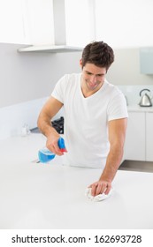 Smiling Young Man Cleaning Kitchen Counter In The House