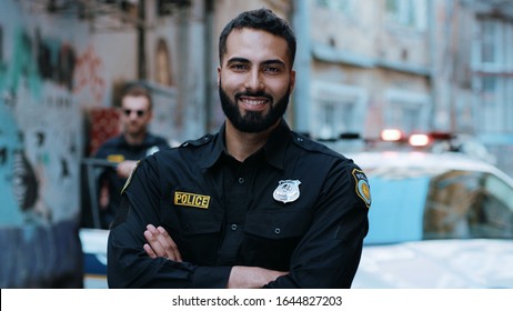 Smiling young man cops stand near patrol car look at camera enforcement happy officer police uniform auto safety security communication control policeman portrait close up slow motion