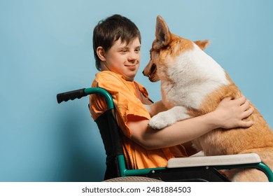 Smiling young man with down syndrome hugging his pet while sitting in a wheelchair on blue background. Love animal concept, health care - Powered by Shutterstock