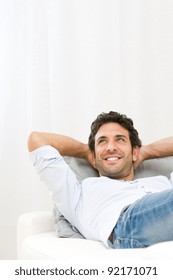 Smiling Young Man Dreaming At His Future And Relaxing On Sofa At Home