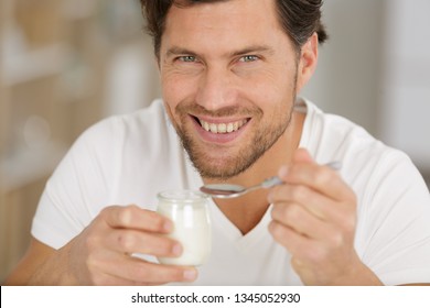 Smiling Young Man Eating Yogurt