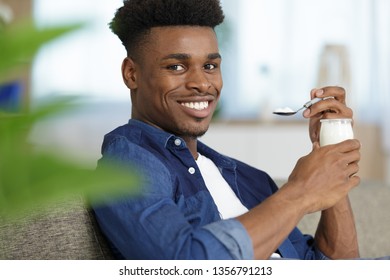 Smiling Young Man Eating Yogurt