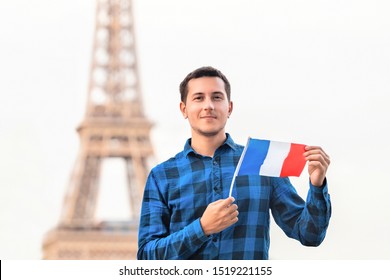 Smiling young man holding a French flag on the background of the famous Eiffel tower. Travel, immigration and study in Paris concept - Powered by Shutterstock
