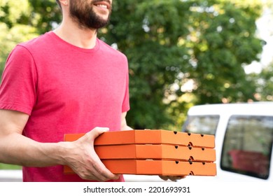 Smiling young man holding pizza boxes outdoors. Pizza delivery. Selective focus. - Powered by Shutterstock