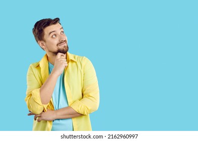 Smiling young man isolated on blue studio background look at empty copy space aside. Happy male think good promotion offer or sale deal, discover possibility or option. Ad, copyspace.