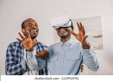 smiling young man looking at happy senior father using virtual reality headset  - Powered by Shutterstock