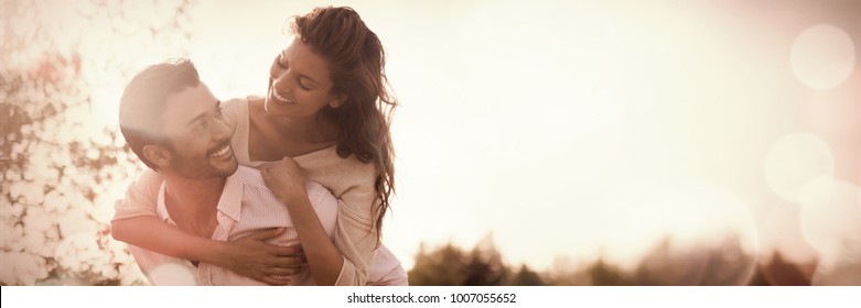 Smiling young man piggybacking woman at farm during sunny day - Powered by Shutterstock