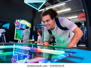 A smiling young man playing games at arcade entertainment center. - Shutterstock ID 2193423119