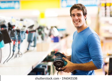 Smiling Young Man Purchasing A Hand Tool In Hardware Shop