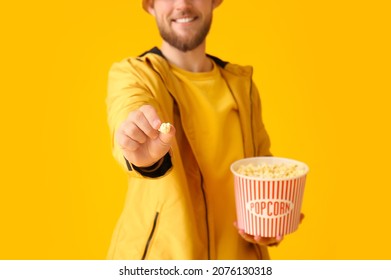 Smiling Young Man Showing Popcorn On Color Background