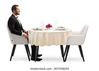 Smiling Young Man Sitting Alone At A Restaurant Table Isolated On White Background