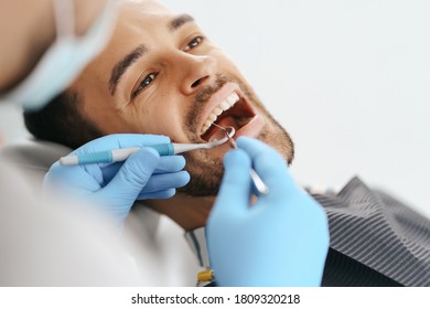 Smiling Young Man Sitting In Dentist Chair While Doctor Examining His Teeth