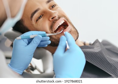 Smiling Young Man Sitting In Dentist Chair While Doctor Examining His Teeth