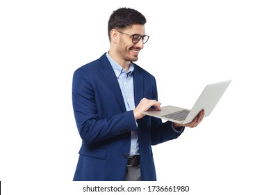 Smiling Young Man Standing In Blue Suit And Glasses, Holding Open Laptop, Watching Funny Content, Feeling Happy And Relaxed, Isolated On White Background