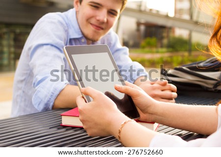 Smiling young man student and a young woman taping on tablet in a city on university bench.Young smiling student  outdoors  with tablet.Life style.City