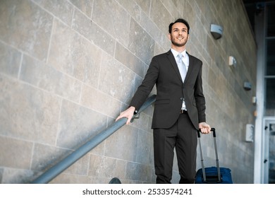 Smiling young man in suit with trolley bag at airport terminal - Powered by Shutterstock