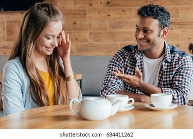 Smiling Young Man Talking To Shy Woman Sitting In Cafe