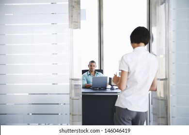 Smiling Young Man Talking To Woman Standing In Doorway At His Office