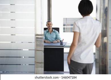 Smiling Young Man Talking To Woman Standing In Doorway At His Office