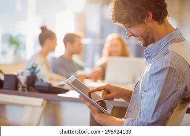 Smiling young man using digital tablet in the office
