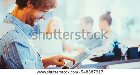 Smiling young man using digital tablet in the office with copy space