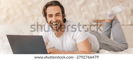 Smiling Young Man Using Laptop Lying On Bed At Home, Home Office Concept