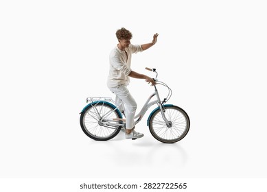 Smiling young man waves while standing beside bicycle. Concept of friendly bicycle rental service, welcoming cycling tourism, positive customer communication.