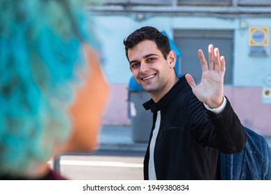 Smiling Young Man Waving To Girl Or Friend On The Street