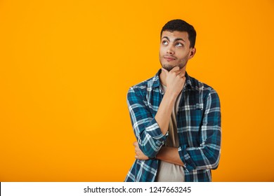 Smiling Young Man Wearing Plaid Shirt Standing Isolated Over Orange Background, Looking Away