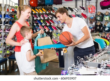 smiling young man and woman buying skateboard for son in sport shop - Powered by Shutterstock